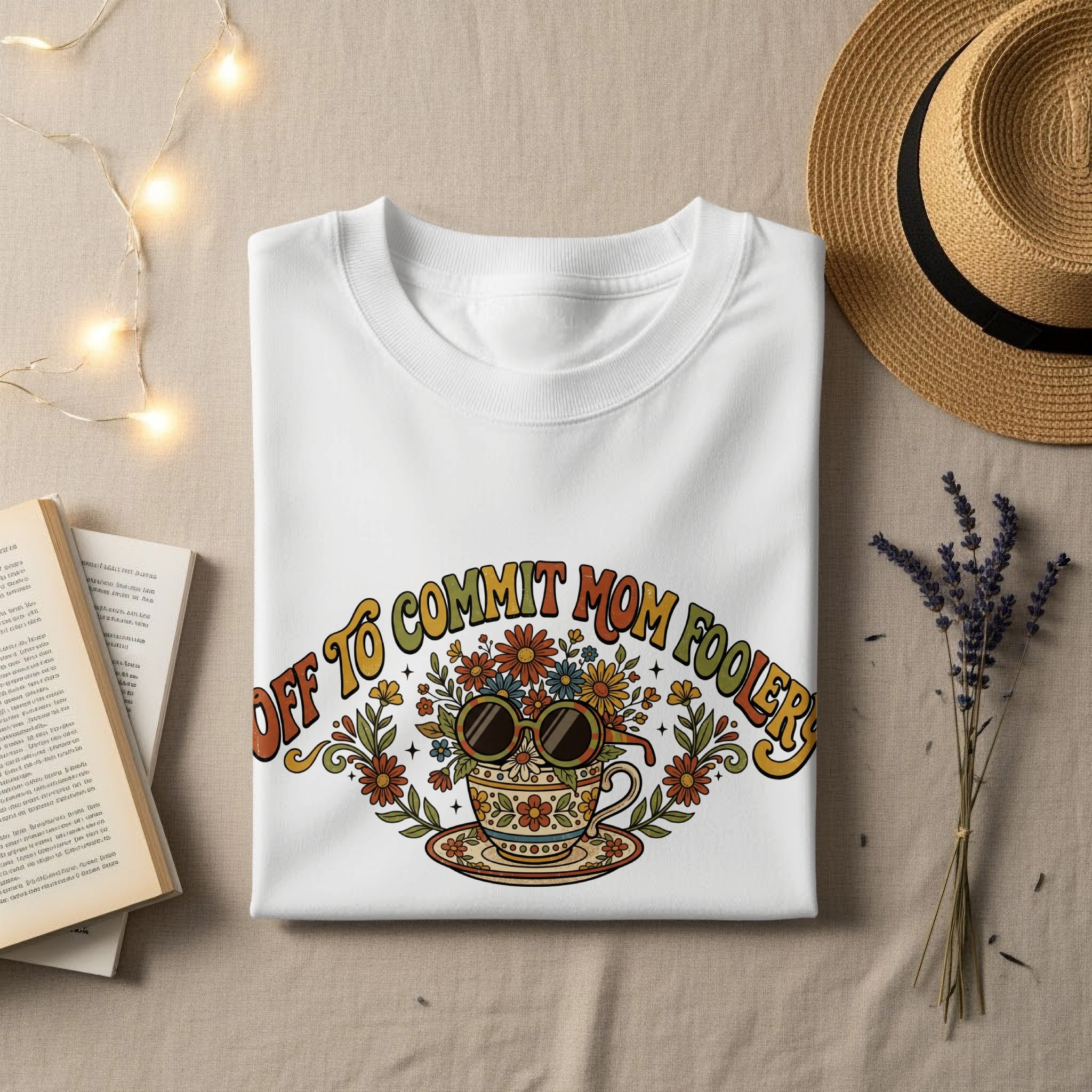 White t-shirt with "Off to Commit Mom Foolery" text and colorful floral teacup graphic.
