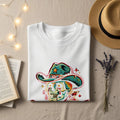 White t-shirt with a skull wearing a cowboy hat and colorful starbursts.