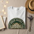 White sweatshirt with "The Good Moms Club 2026" logo.
