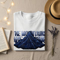 White t-shirt with blue geometric mountain graphic and text "THE MOUNTAINS ARE CALLING".