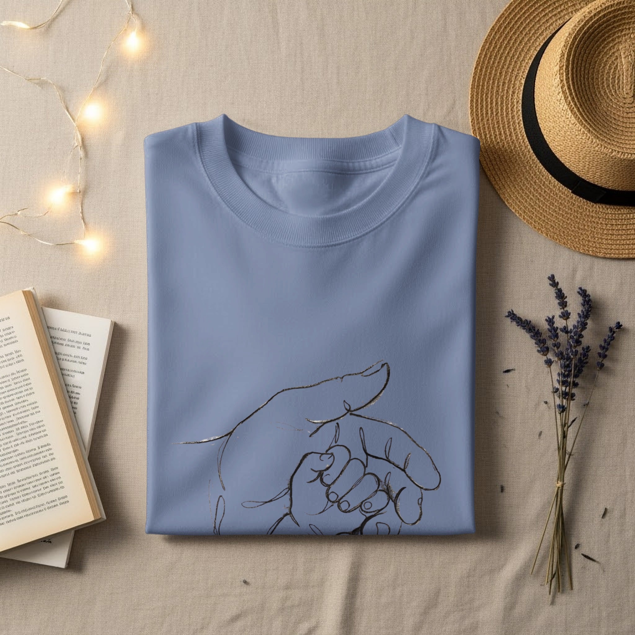Light blue t-shirt with line art of an adult hand holding a baby's hand.
