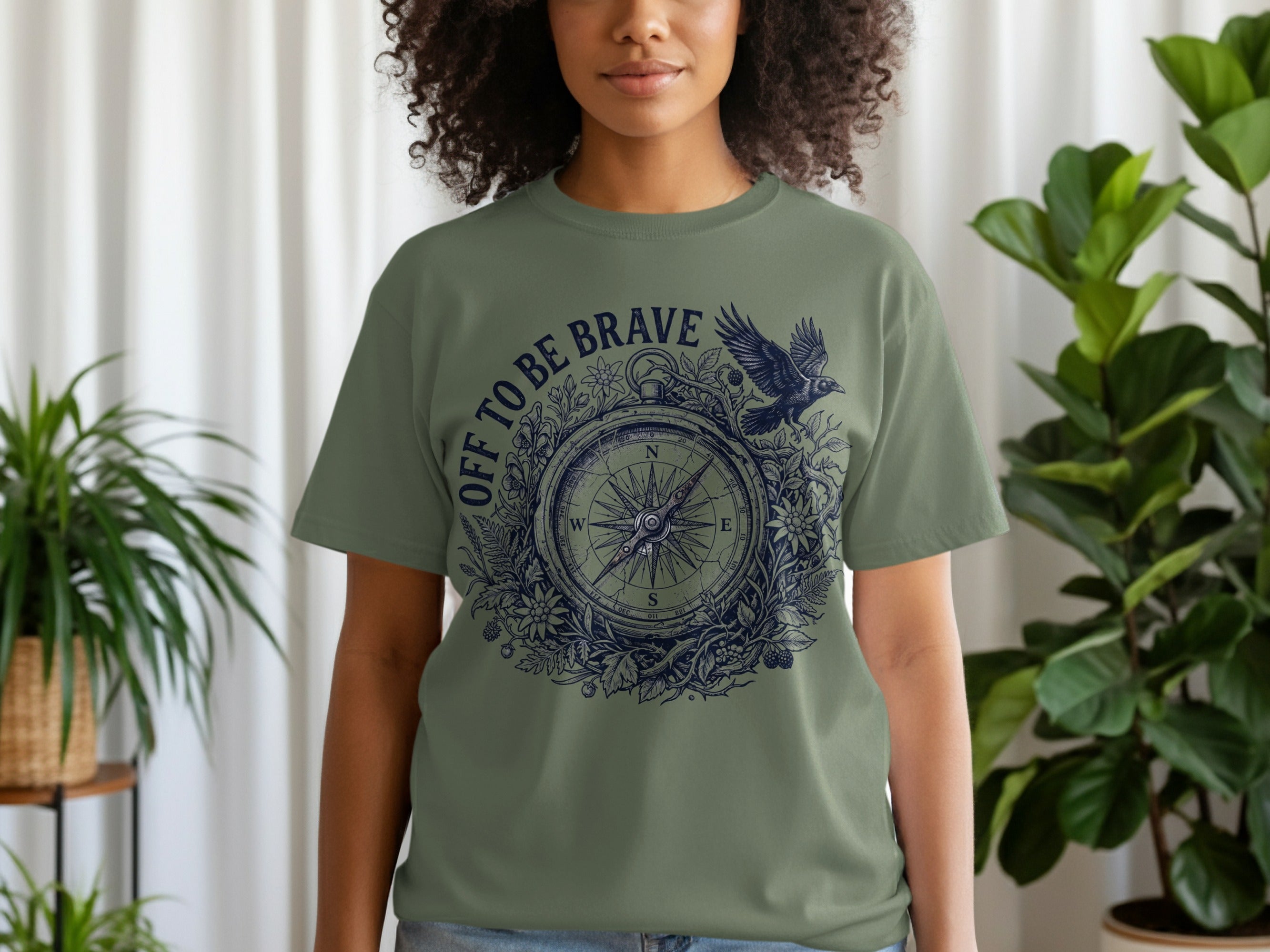 Olive green t-shirt with a circular compass design and "OFF TO BE BRAVE" text.