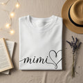 White t-shirt with "mimi" and a heart design.