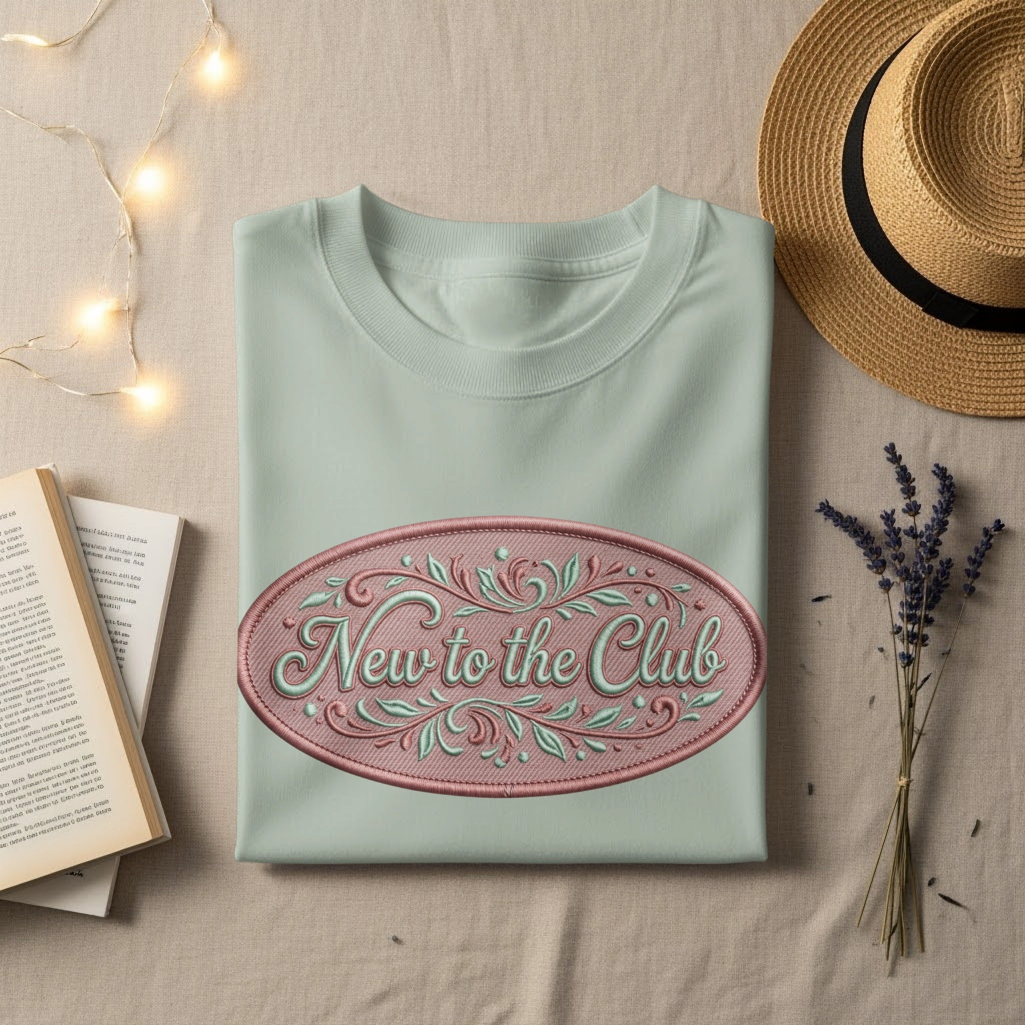 Light green t-shirt with embroidered oval "New to the Club" text.