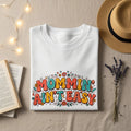 White sweatshirt with colorful "Mommin Ain't Easy" text and floral accents.