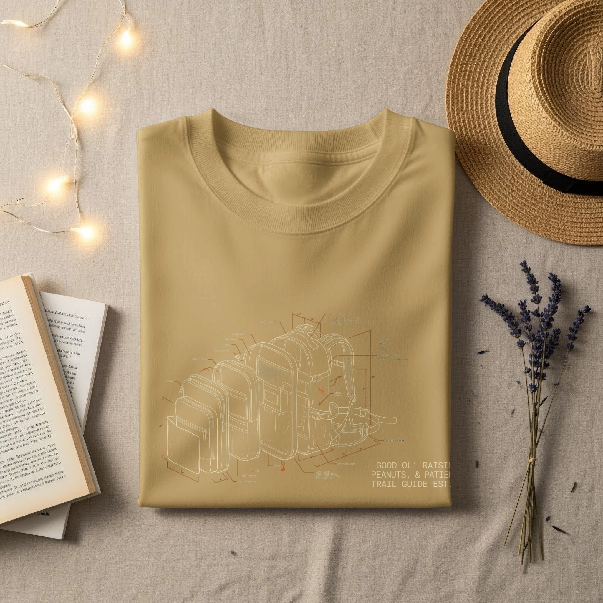 Tan t-shirt laid flat with blueprint illustration of backpack and text.