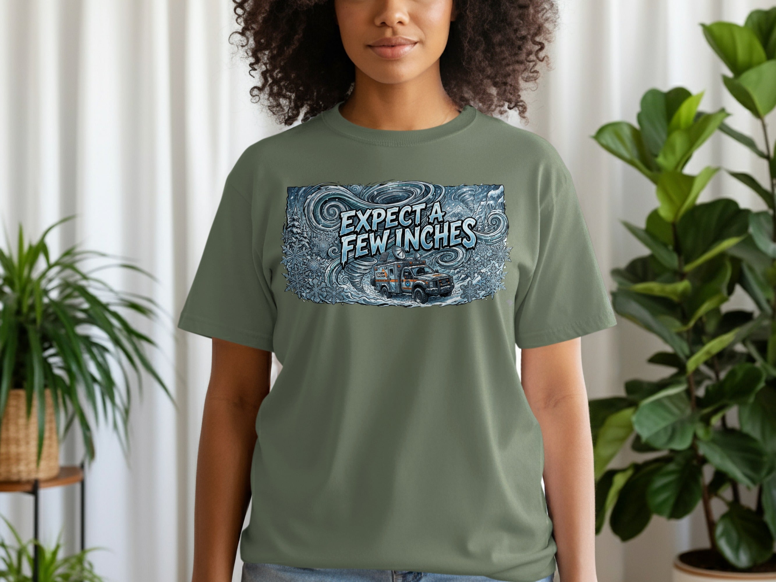 Olive green t-shirt with "EXPECT A FEW INCHES" and ambulance graphic.