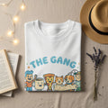 White t-shirt with "THE GANG" and cartoon characters of a mug, pizza, cat, and dog.