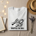 White t-shirt with "DROPPED THE BALL" text and graphic of hands reaching for a football.