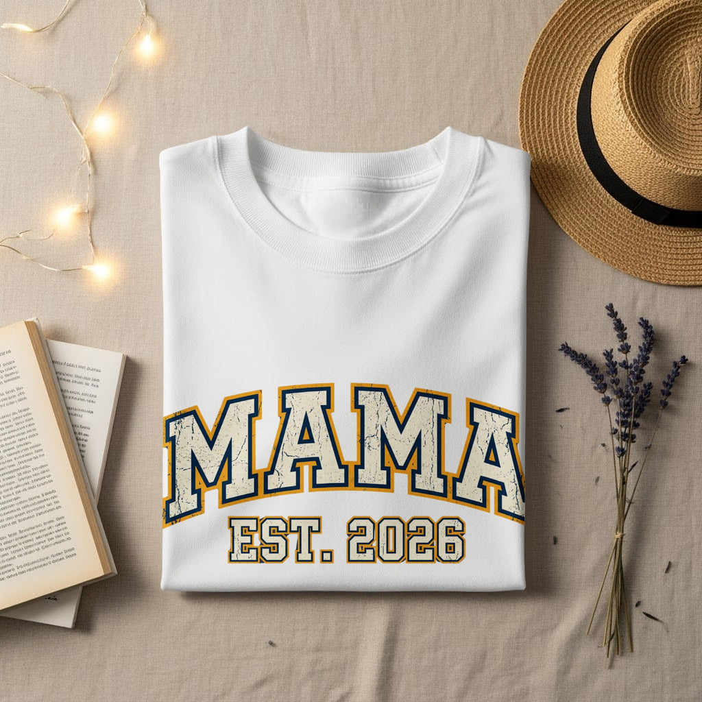 White sweatshirt with "MAMA EST. 2026" in distressed blue and gold lettering.
