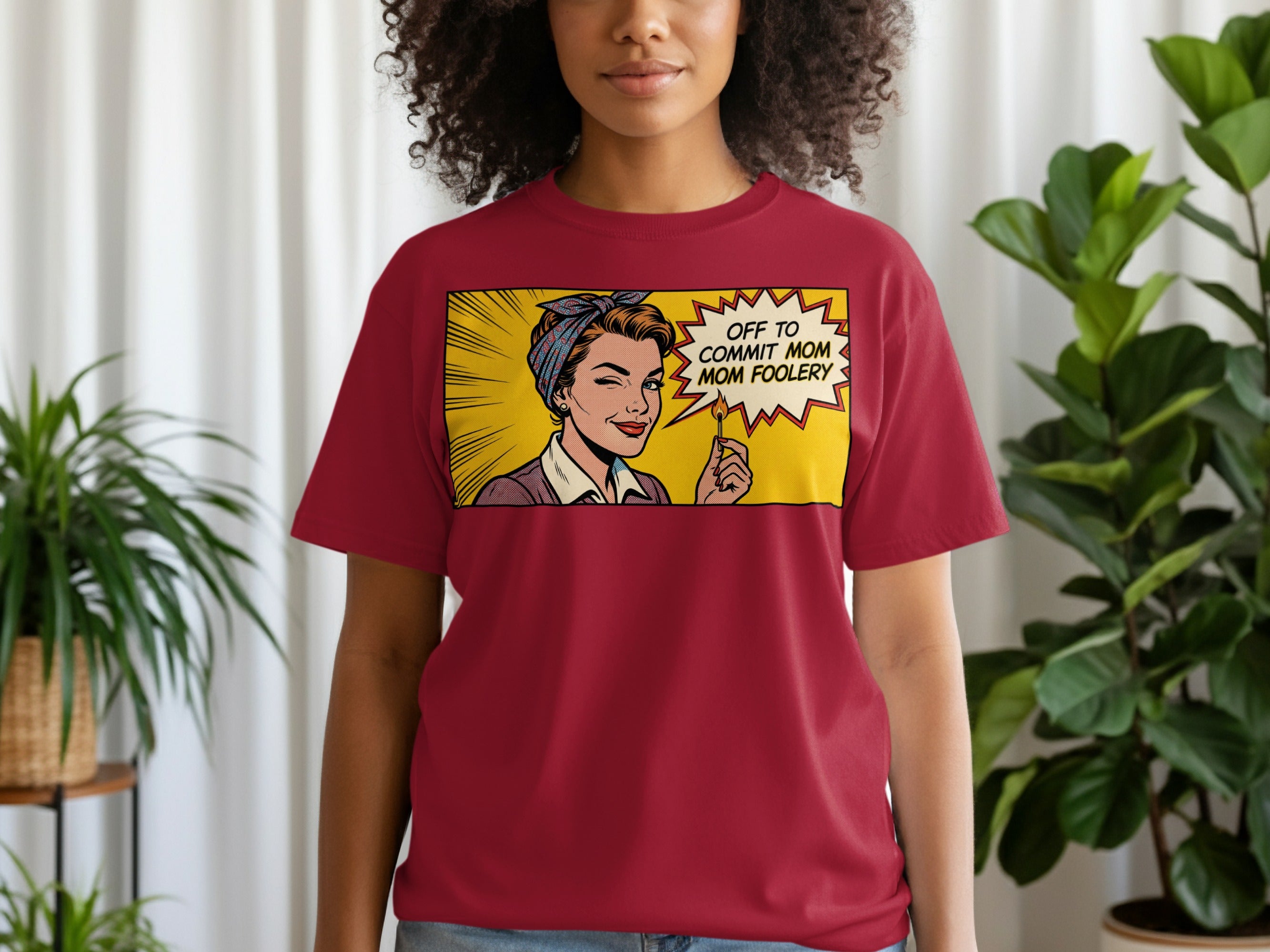 Woman in maroon t-shirt wearing a pop art comic panel saying "OFF TO COMMIT MOM FOOLERY".