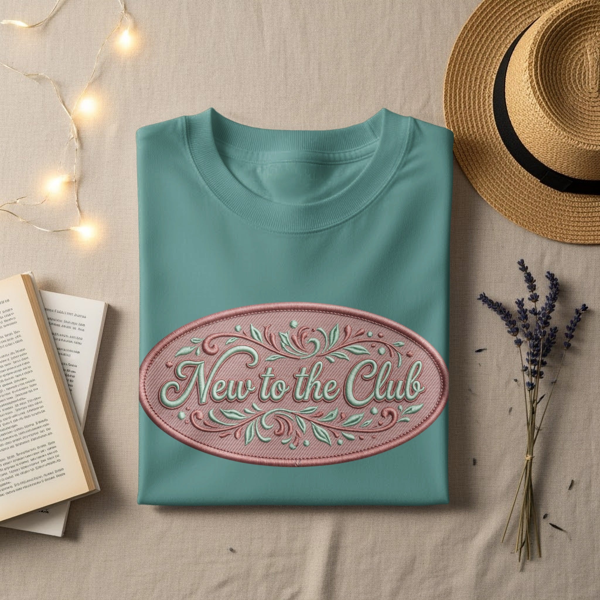 Teal t-shirt with "New to the Club" embroidered oval design.