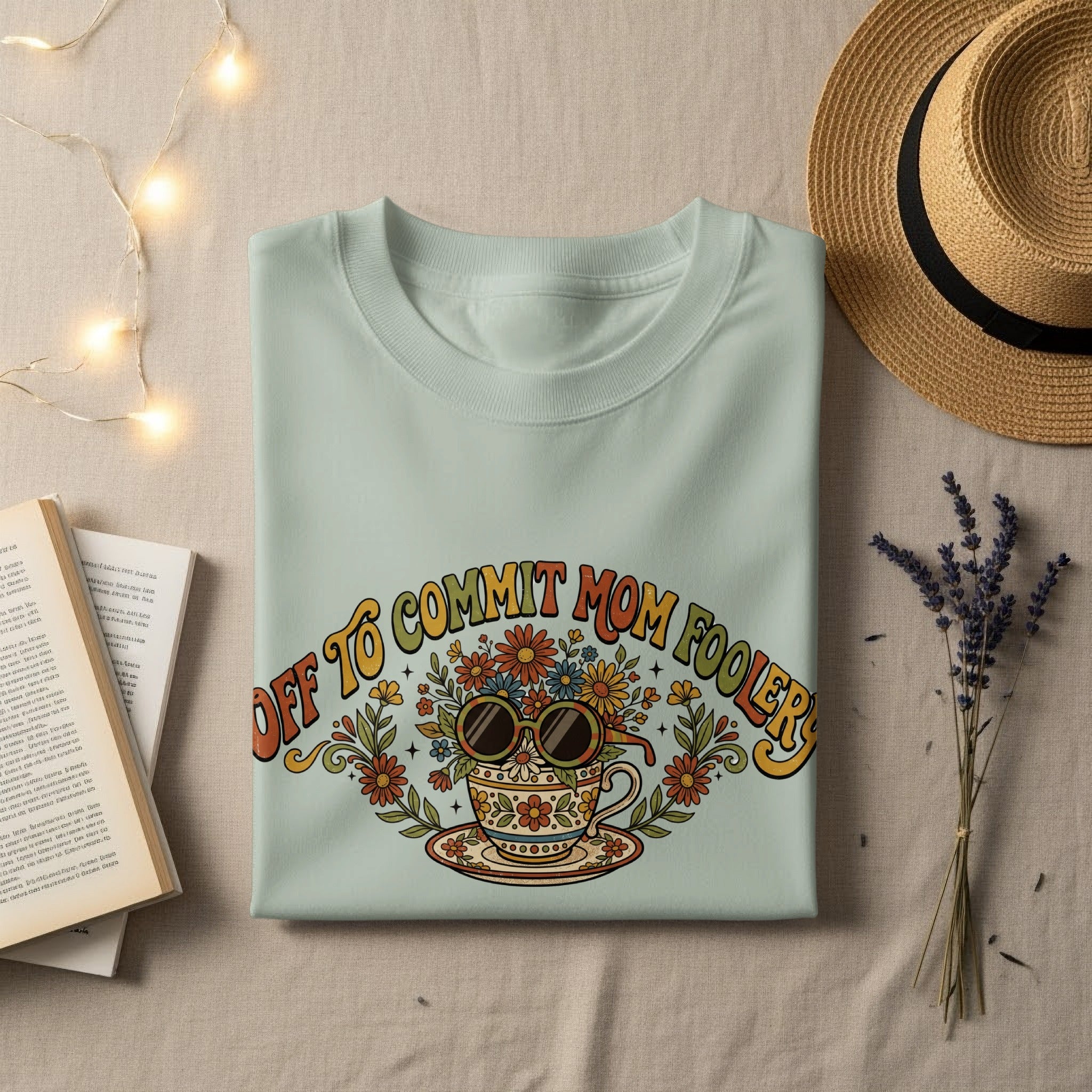 Light green t-shirt with "Off to Commit Mom Foolery" text and floral sunglasses in a teacup.