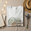White t-shirt with "Daddy's Pickleball Buddy" graphic.
