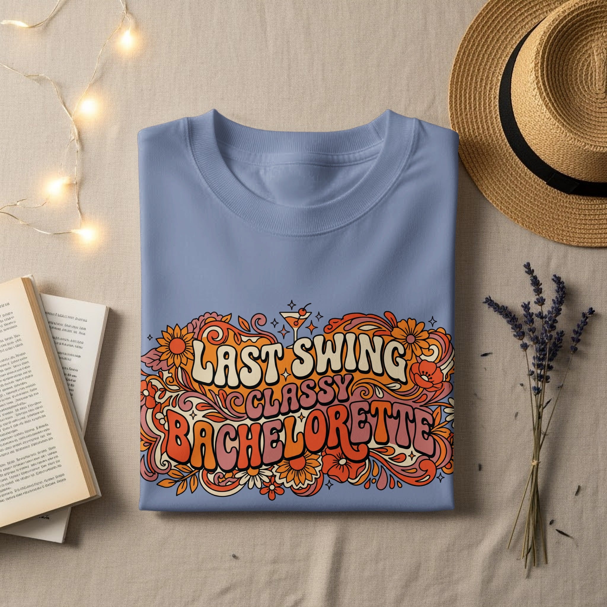 Light blue t-shirt with "Last Swing Bachelorette" in retro floral text.
