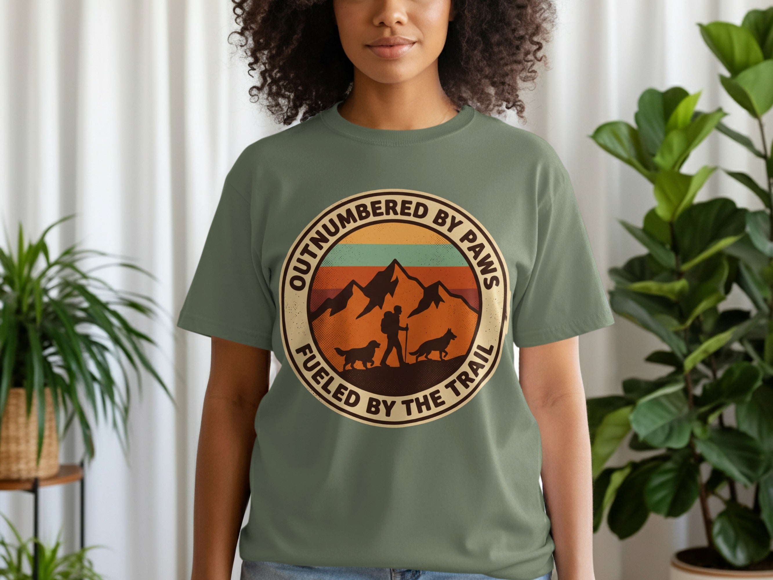 Green t-shirt with circular graphic of mountains, dogs, and text.
