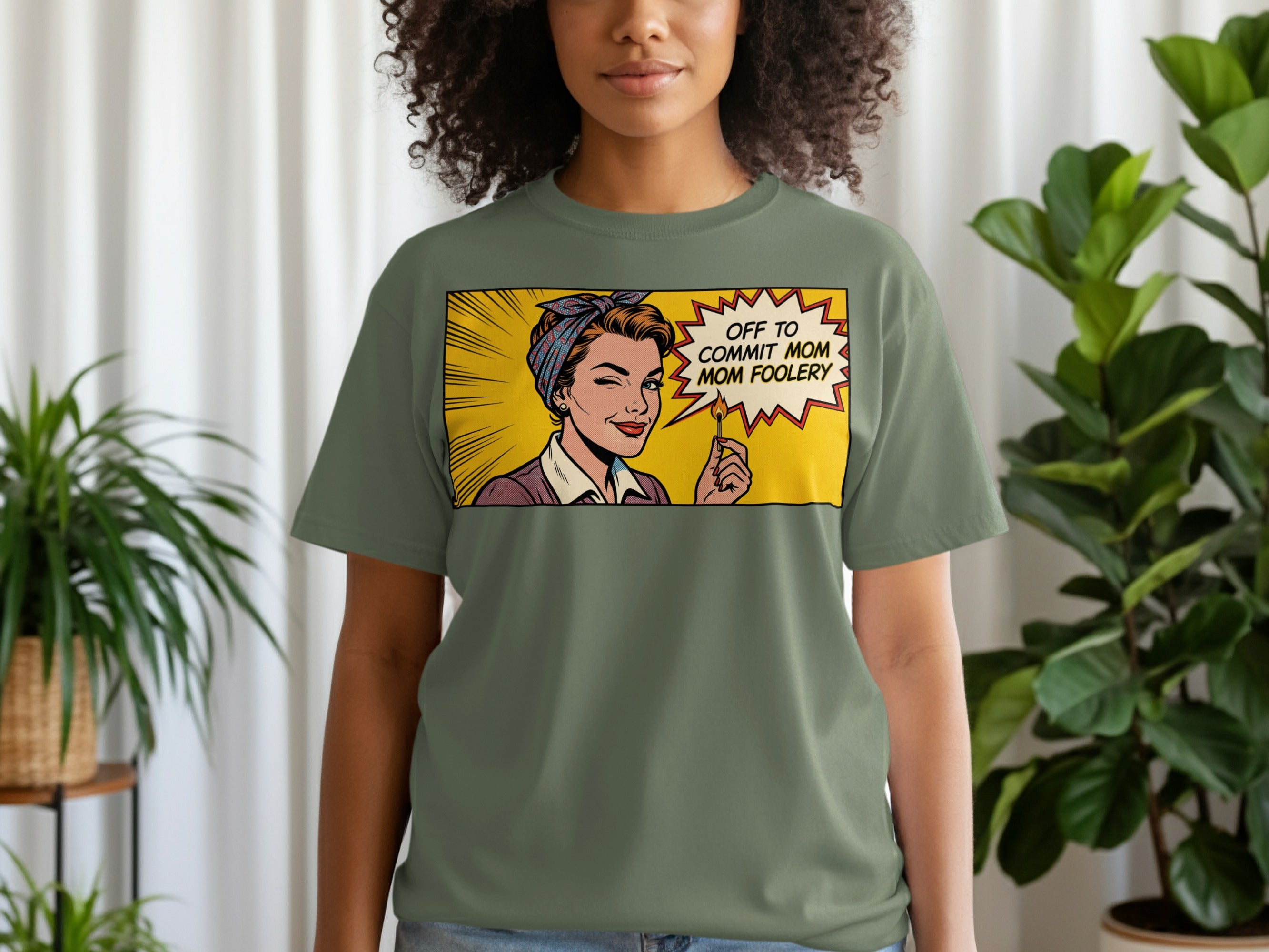 Olive green t-shirt with comic pop art graphic of a woman saying "Off to commit mom foolishness".